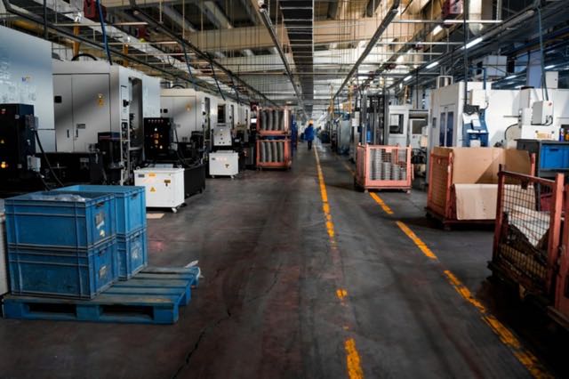 Allée d’un atelier de production entre machines, caisses et palettes