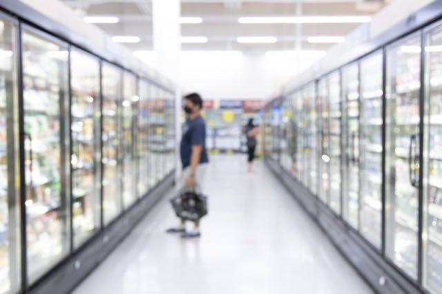 Allée de vitrines réfrigérées dans un magasin d’alimentation, un client au fond